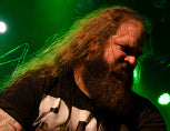 Antonio Arajo portrait with long hair and beard under dramatic green stage lighting.