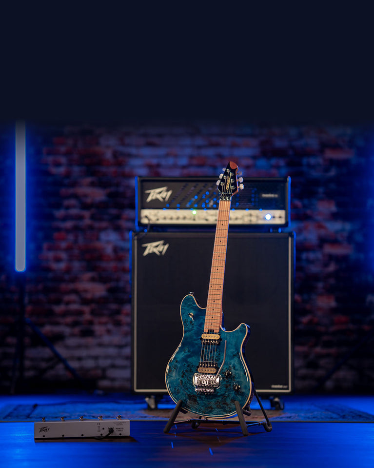 Peavey HP2 Poplar Burl electric guitar in translucent blue finish displayed on guitar stand with full Peavey tube amplifier half-stack rig