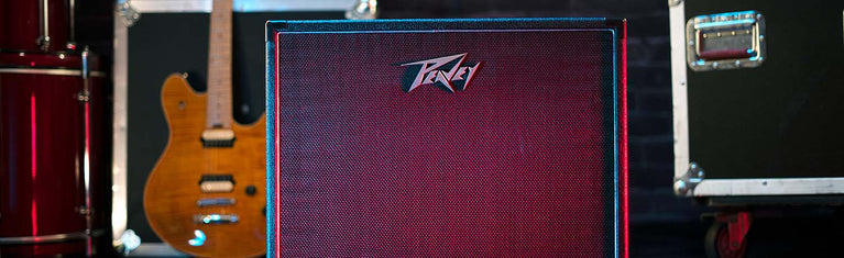 Peavey amplifier with a guitar and equipment cases in the background